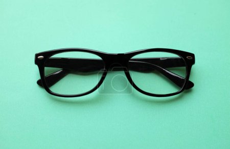 Téléchargez les photos : Gros plan et plat déposer un moderne lunettes, lunettes, lunettes, lunettes montures noires mode pour les hommes et les femmes sur l'isolat lumineux sur un fond vert pastel - en image libre de droit