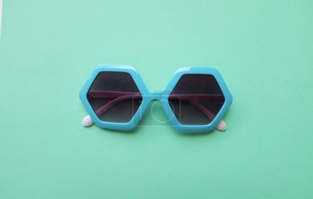 Téléchargez les photos : Fermer bleu pentagone lunettes de soleil isoler sur un fond vert pastel - en image libre de droit