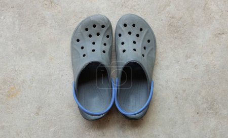 un par de zuecos azules aislados en el cemento. zapatos de verano aqua con agujeros y correa en las pizarras de silicona del talón . 