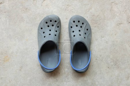 un par de zuecos azules aislados en el cemento. zapatos de verano aqua con agujeros y correa en las pizarras de silicona del talón . 