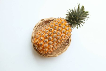 Téléchargez les photos : Frais un ananas (ananas comosus (l.) merr) jaune mûr biologique dans un panier de bambou isoler sur une toile de fond blanche. concept de fruits d'été. - en image libre de droit