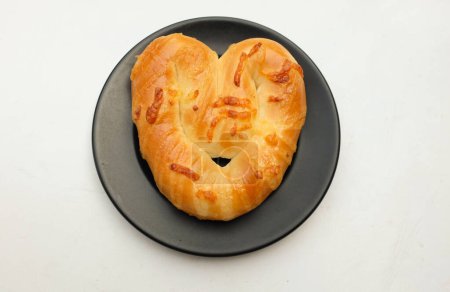 Téléchargez les photos : Délicieux fait maison un pain fraîchement cuit boulangerie en forme de coeur, bretzels doux, pain danois en céramique noire plaque noire sur un fond blanc. pour Valentine. Idéal pour les amoureux - en image libre de droit