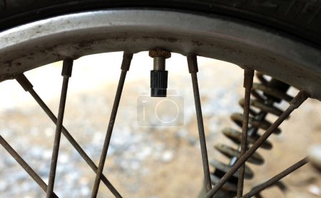 Foto de Primer plano de una válvula de neumático de motocicleta, El orificio de llenado de aire en la rueda de la motocicleta cuando la posición está abierta, vástago de válvula de neumático con tapa. válvula de tapa negra - Imagen libre de derechos