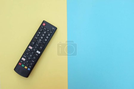 Photo for Remote control tv isolate on two tone yellow blue paper color for background.concept of watching tv.top view with place for text. - Royalty Free Image