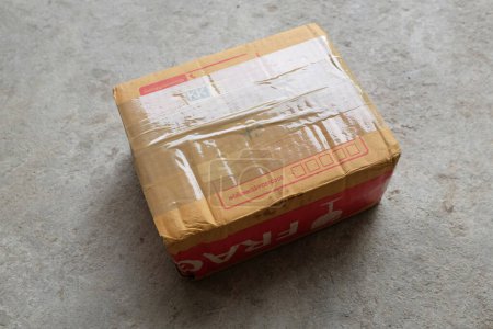 Foto de Cerrar una caja de correo marrón, caja de papel, cajas de cartón grabadas, cartón aislado sobre un fondo de cemento. Entrega y envío concepto en línea - Imagen libre de derechos