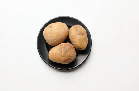 Téléchargez les photos : Tas de pommes de terre fraîches crues de bébé (Solanum tuberosum) tête ou jeune pomme de terre dans un plat en céramique isolé sur un fond blanc - en image libre de droit