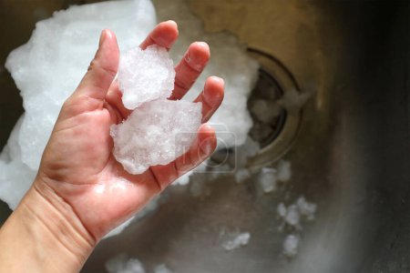 Foto de Mano humana sostiene cristales de hielo del congelador en refrigerador - Imagen libre de derechos