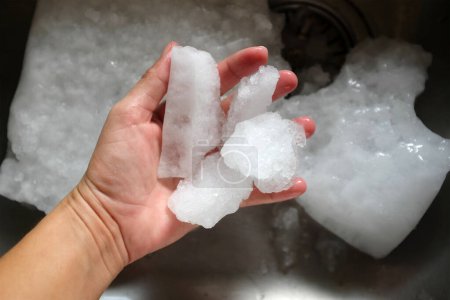 Téléchargez les photos : Main humaine tient cristaux de glace decongélateur au réfrigérateur - en image libre de droit