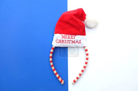 Foto de Hermosa diadema decorativa de Santa Sombrero rojo aislado en un fondo azul y blanco.concepto de fiesta de Navidad alegre, Año Nuevo viene pronto, decoración de temporada festiva con elementos de Navidad - Imagen libre de derechos