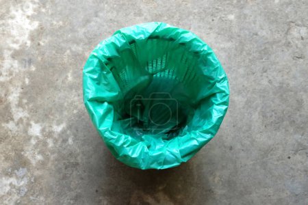 poubelle avec sacs en plastique vert isolé sur le fond de ciment.symbole de la gestion des déchets et de l'environnement