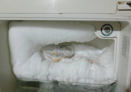weißer Kühlschrank mit Gefrierfach ist geöffnet.große Menge Eis im Gefrierfach, Eis in einem leeren KühlschrankLeerer Kühlschrank mit Eis. Eis im Gefrierfach im Kühlschrank