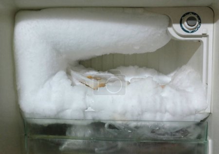 weißer Kühlschrank mit Gefrierfach ist geöffnet.große Menge Eis im Gefrierfach, Eis in einem leeren KühlschrankLeerer Kühlschrank mit Eis. Eis im Gefrierfach im Kühlschrank