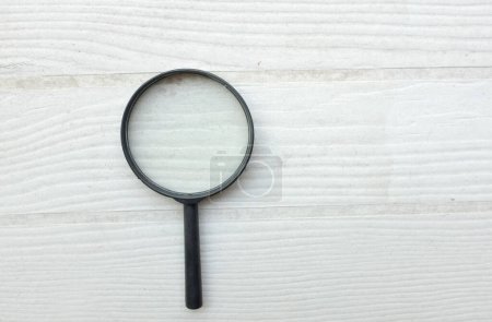 top view and close up magnifying glass loupe search symbol isolate on the wooden table white backdrop.Searching information data on internet ,Minimal creative concept. 
