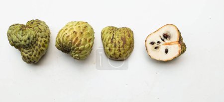 fresh green raw custard apple,sugar apple, annona cherimola (annona squamosa l.) fruit cut in half sliced with leaves isolated on white backdrop. tropical exotic fruit and healthy fruits