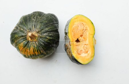 A pile of fresh raw green Japanese pumpkin (Cucurbita moschata) ,Kabocha squash,both in ball and cut, showing yellow flesh isolated on a white backdrop.Healthy food vegetable, fruit, and food business