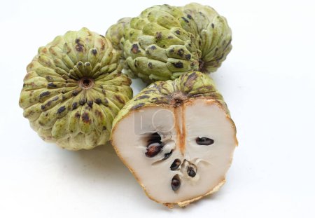 fresh green raw custard apple,sugar apple, annona cherimola (annona squamosa l.) fruit cut in half sliced with leaves isolated on white backdrop. tropical exotic fruit and healthy fruits