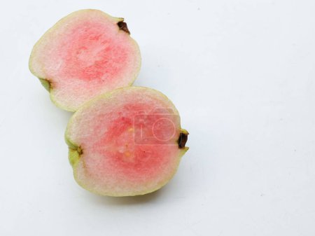 Foto de Guayaba rosada madura dulce, guayaba roja (psidium guajava) fruta con hojas verdes y medias rebanadas, entera aislada sobre fondo blanco, vista superior, puesta plana, concepto de fruta saludable - Imagen libre de derechos