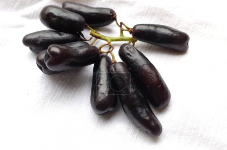 Bunch of fresh Sweet black seedless Moon Drops grape,Purple Witch Finger grapes,Sapphire Grapes or Witch Fingers grape isolated on white backdrop.black grapes. Grapes black taste sweet growing nature