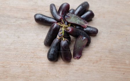 Bunch of fresh Sweet black seedless Moon Drops grape,Purple Witch Finger grapes,Sapphire Grapes or Witch Fingers grape isolated on a wooden table backdrop.black grapes. Grapes black taste sweet growing nature