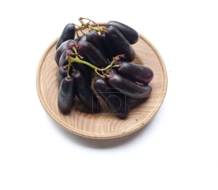 Ein Bündel frischer schwarzer kernloser Moon Drops-Trauben, Purpurroter Hexenfinger-Trauben, Saphir-Trauben oder Hexenfinger-Trauben in einer weißen Holzschale auf weißem Hintergrund. Schwarze Trauben. 