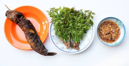 Blick von oben auf einen Neem, siamesischen Neem-Baum, (Azadirachta indica) Gemüse mit süßer Sauce (thailändischer Name ist Sadao nam pla wan) und gegrilltem Wels in der Küche zum Servieren, traditionelle thailändische Küche 