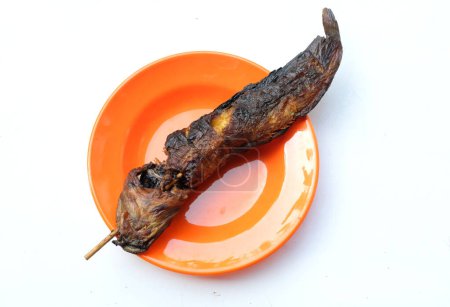 top view a grilled catfish skewers ,(clarias) ,freshwater fish in plate orange on white backdrop. concept local thai delicious street food in thailand. high protein. healthy eating. fish menu.