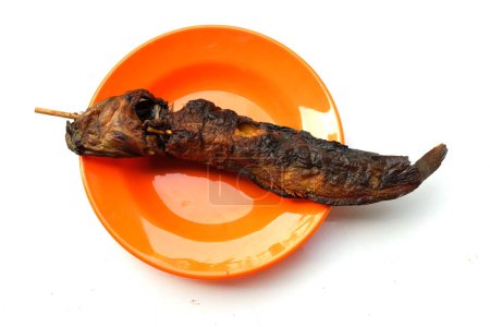 top view a grilled catfish skewers ,(clarias) ,freshwater fish in plate orange on white backdrop. concept local thai delicious street food in thailand. high protein. healthy eating. fish menu.