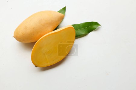 ripe yellow mango golden ,mango nam dok mai mango ,barracuda mango ( mangifera indica) king of fruit cut in half sliced with leaves isolated on a  white backdrop.tropical exotic fruit and healthyfruit