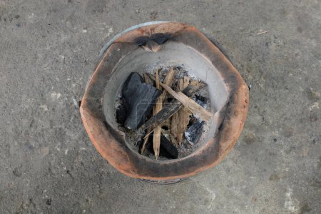 Image of a charcoal turtle,brazier stove  on a cement floor.rural outdoor cooking thai style.pottery stove ashes rural Thailand, which has been used for a long time