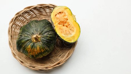 A pile of fresh raw green Japanese pumpkin (Cucurbita moschata) ,Kabocha squash, in a wicker basket isolated on a white backdrop.Healthy food vegetable, fruit, and food business idea