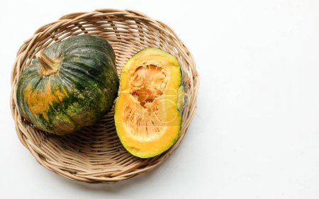 A pile of fresh raw green Japanese pumpkin (Cucurbita moschata) ,Kabocha squash, in a wicker basket isolated on a white backdrop.Healthy food vegetable, fruit, and food business idea