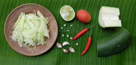 Nouilles de papaye hachées ou papayes crues hachées le long d'une assiette en bois sur le fond de la feuille de banane, pour préparer un menu de salade de papaye ou Som Tam appel thaïlandais. salade de papaye Saveur épicée, nourriture thaï, thaï traditionnel 