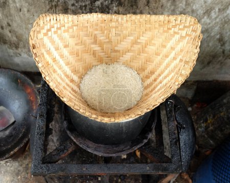 Ansicht von oben und schließen Sie einen alten thailändischen klebrigen Reisdämpfer im Topf auf Herd mit schmutzigem Rußfleck Betonwand Hintergrund. Reis kochen, Klebreis, heißer Klebreis in altem Holzdämpfer.