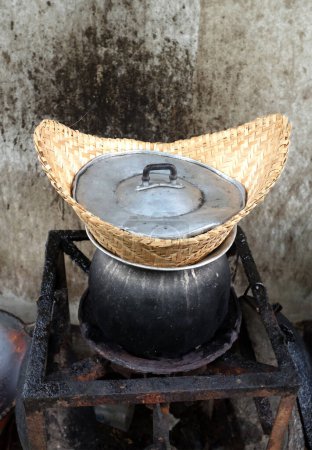 top view and close up a old thai sticky rice steamer in pot on stove with dirty soot stain concrete wall background. cook rice,sticky rice,hot sticky rice in old wooden steamer.