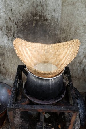 vista superior y cerrar un viejo vapor de arroz pegajoso tailandés en olla en la estufa con sucia mancha de hollín fondo de pared de hormigón. cocinar arroz, arroz pegajoso, arroz pegajoso caliente en vapor de madera vieja.