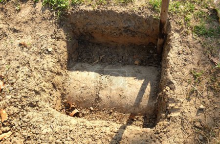 Photo for Dig a hole for placing the concrete pillar.Dug out rectangular pit. Close-up Texture.square shaped hole into the middle of the lawn. - Royalty Free Image