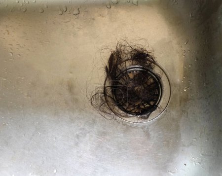 close up a waste hair fragments cause clogged pipe in the sink in kitchen drain.housekeeping concept
