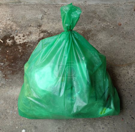 one green trash bags lay on the ground.  pile of large plastic bag waste. smelly trash pile green bag. dirty disposal dump smelly trash.concept environmental protection,waste management andenvironment