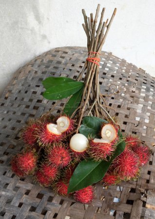 close up a fresh ripe red rambutans (Nephelium lappaceum)whole and half  and green leaf isolate on a white backdrop.Rambutan is a fruit with a red peel, white flesh, brown seeds. It has a sweet taste,