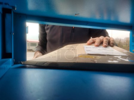 Foto de Vista subjetiva desde el interior, de una mano recogiendo un paquete depositado en un casillero - Imagen libre de derechos