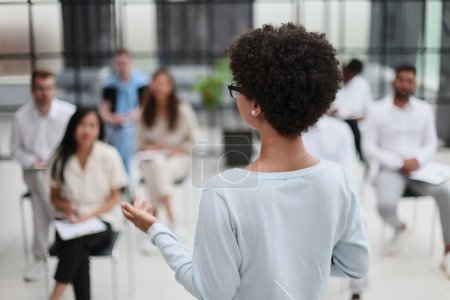 Téléchargez les photos : Orientation sélective de la jeune femme d'affaires avec des collègues interraciaux pendant le séminaire - en image libre de droit