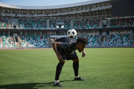Téléchargez les photos : Un joueur de football s'entraîne à tenir le ballon avec le dos. Joueur de football afro-américain en formation. - en image libre de droit