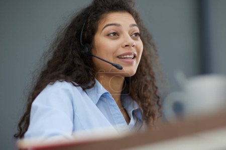 Brunette business woman using headset to communicate and advise people in customer service office. Call centre.