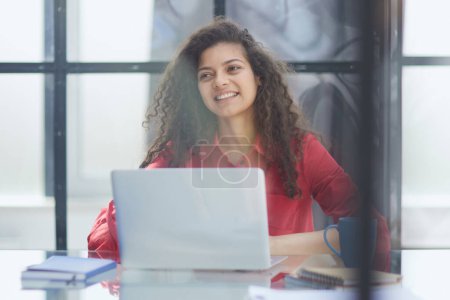 Foto de Retrato de una joven empresaria caucásica exitosa sentada en el escritorio trabajando en una computadora portátil en la oficina de la ciudad - Imagen libre de derechos
