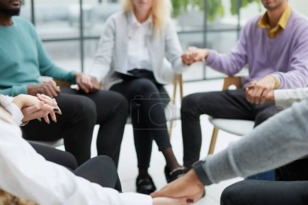 Foto de Diversas personas sentadas en círculo tomados de la mano en la terapia de grupo - Imagen libre de derechos