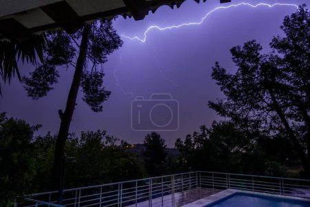 Téléchargez les photos : Foudre orageuse sur un paysage en face d'une piscine - en image libre de droit