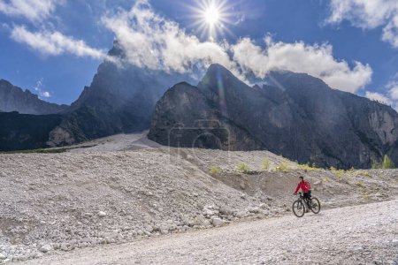 Photo for Pretty senior woman riding her electric mountainbike in the Innerfeld Valley in the Sexten Dolomites near village of Innichen , Tre cime National park, South Tirol, Italy - Royalty Free Image