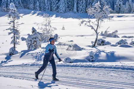 Foto de Mujer mayor agradable y activa esquí de fondo en la zona de Hochhaedrich del bosque de Bregenz en Vorarlberg, Austria - Imagen libre de derechos