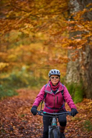 Téléchargez les photos : Belle femme âgée chevauchant son vélo de montagne électrique sur les sentiers forestiers automnaux près de Stuttgart, - en image libre de droit