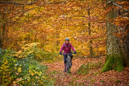 Téléchargez les photos : Belle femme âgée chevauchant son vélo de montagne électrique sur les sentiers forestiers automnaux près de Stuttgart, - en image libre de droit